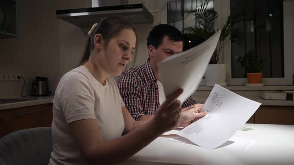 Happy Couple Smiling Each Other After Calculating Monthly Loan and Tax Payment on Kitchen at Night alt