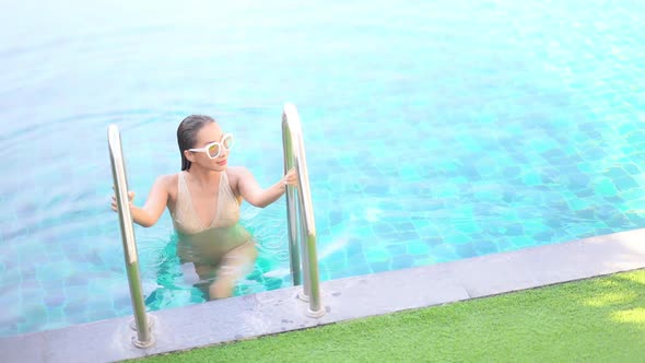Young asian woman enjoy around outdoor swimming pool for leisure alt