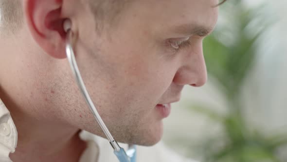 Young Male Doctor Puts on Phonendoscope and is Ready to Listen to Lungs of Sick Patient at His Home alt