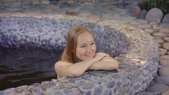 Young Woman Relaxes in a Stone Bath Filled with Healing Herbal Infusions alt