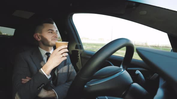 Relaxed Businessman Experience to Riding an Autonomous Self Driving Car and Drink a Coffee alt