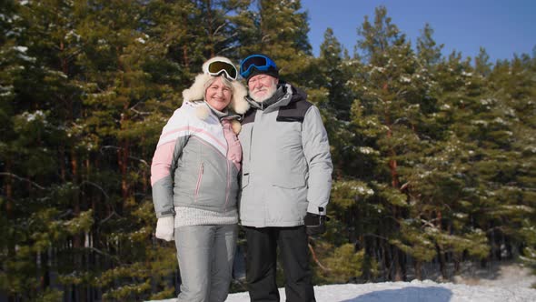 Portrait of Adorable Pensioners Having Fun While Walking in Winter Forest in Sunny Weather Smiling