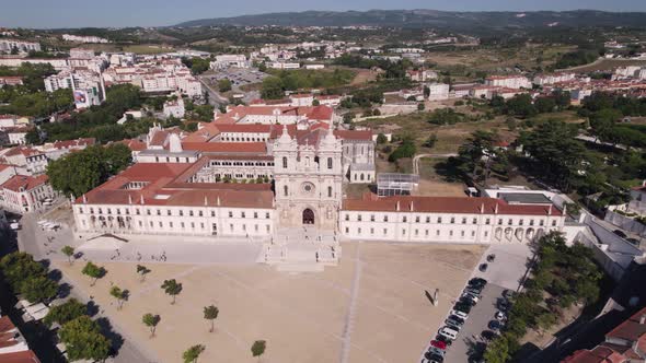 Aerial pull out shot reveals spectacular Alcobaça Monastery catholic monastic complex and cityscape. alt
