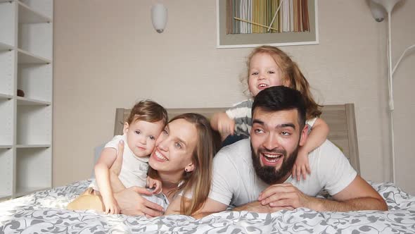 Happy Cheerful Friendly Family Lying on the Bed alt