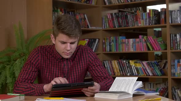 Student Using His Digital Tablet in a Library, Preparing for Abstracts. Close Up, Slow Motion alt