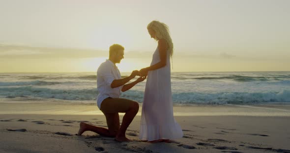 Man proposing to a woman on his knee at beach 4k