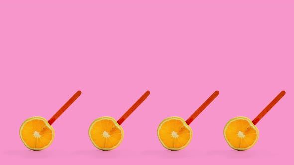 Four Sliced Orange Fruit Popsicle Rotating, Pink Background