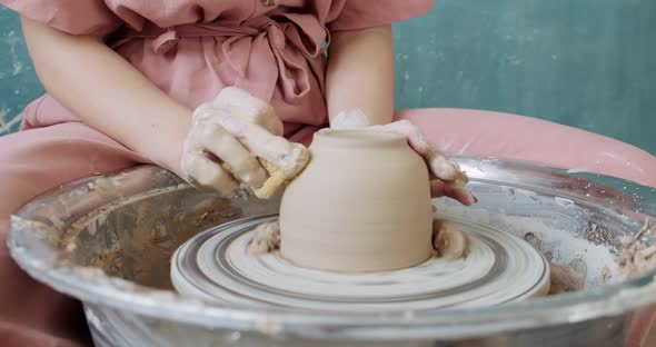 Female Potter Sitting and Makes a Cup on the Pottery Wheel. Woman Making Ceramic Item. Pottery alt