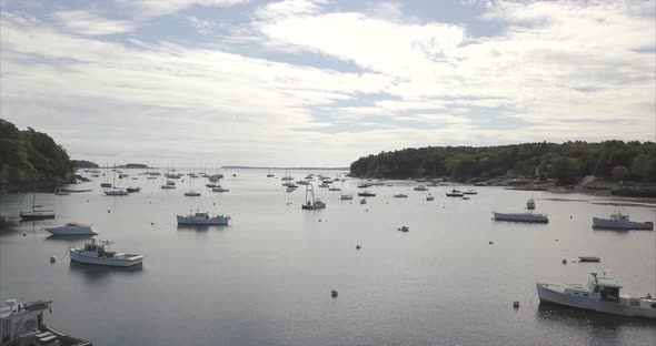 Flying out to sea over Rockport Harbor, Maine with boats below. alt