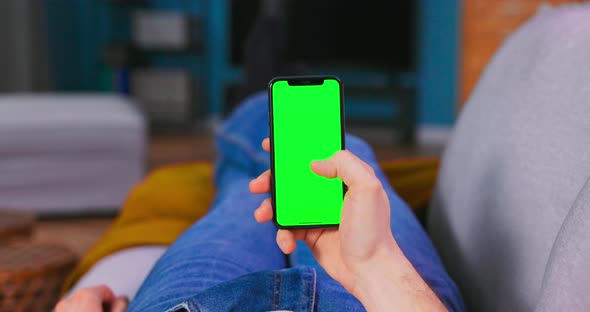 Krakow Poland  Febryary 24 2021 Man at Home Lying on a Couch Using Smartphone alt