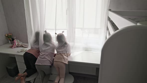 Three children looking out a window