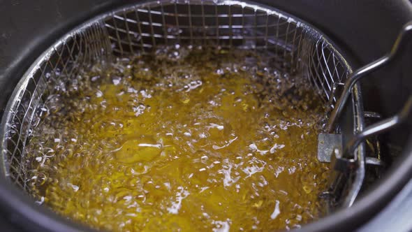 a Basket of Potatoes is Lowered Into the Deep Fryer alt