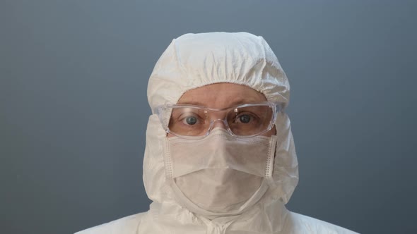 Portrait of masked laborant on gray back.