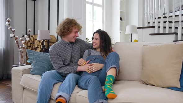 Young Pregnant Woman Relaxing on the Couch Together with Her Lucky Curly Husband alt