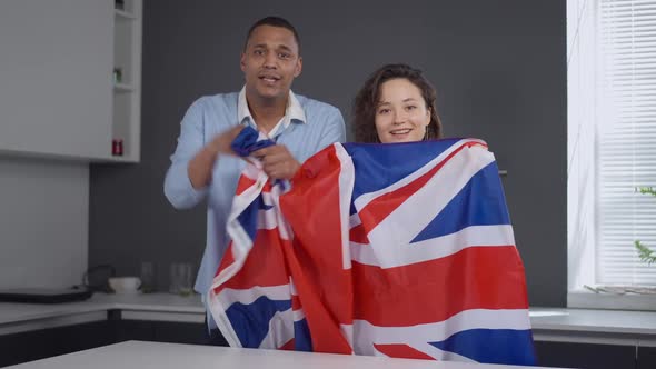 TV POV of Young Interracial Couple with British Flag Rejoicing Winning of National Team in Sports alt