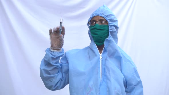 Doctor in PPE kit blue protective suit, surgical mask latex gloves. doctor holding syringe alt