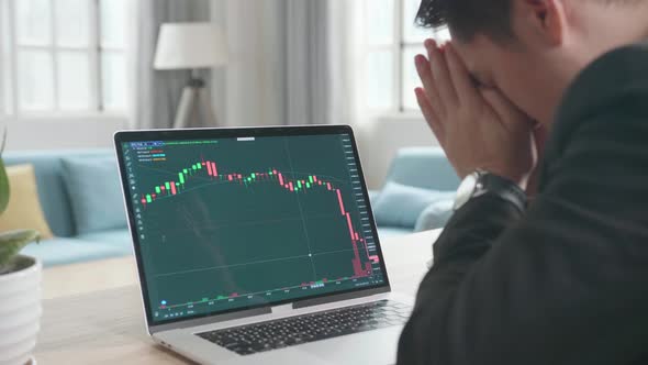 Upset Asian Businessman After Seeing Stock Prices Fall In The Trading On Computer Screen alt
