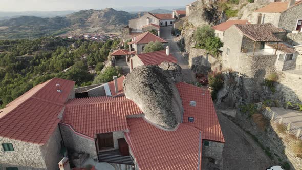 Rock houses with giant boulders in Monsanto village Portugal, drone orbital shot