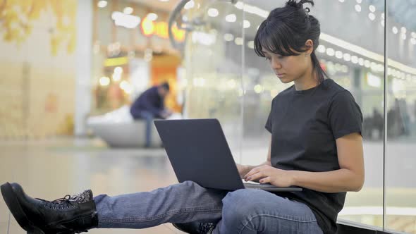 Asian Young Woman Sitting on the Floor with Laptop in Shopping Center Mall