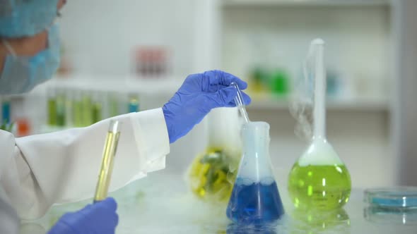 Scientist Adding Blue Liquid in Tube With Yellow Oily Substance, Biofuel Testing alt