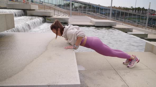 Sporty Woman is Doing Pushups in Urban Landscape Healthy Lifestyle of Townspeople alt
