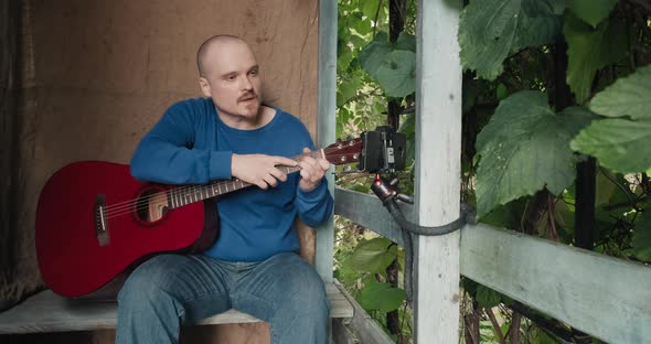 Man in Nature Takes Online Lessons on the Acoustic Guitar