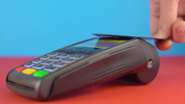 Contactless Payment with Credit Card and Terminal Close Up on Color Background