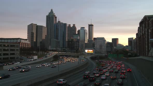 Static, wide shot of the Atlanta Skyline with traffic below in a darkening scene. alt