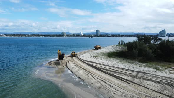 Unique drone view of heavy machinery working on a coastal sand replenishment project close to a urba alt