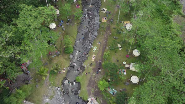 Top shot of tourists bathing in a rocky stream surrounded by dense vegetation all around. People ref alt