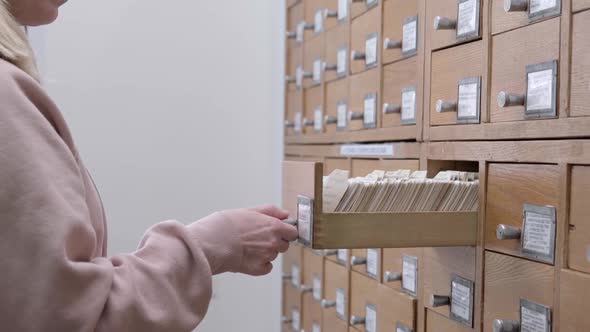 A Young Caucasian Woman is Looking for Information in a File Cabinet alt
