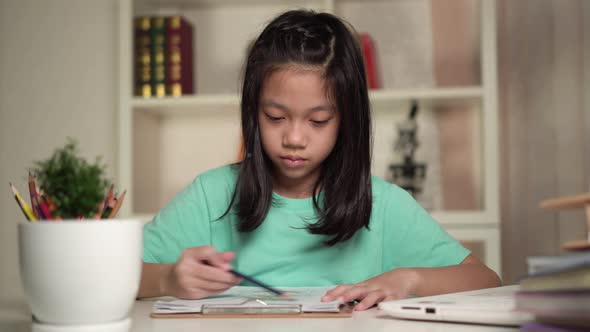 Asian kid girl is drawing and painting, Cute little child draws with colored pencils at home