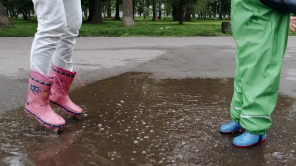Funny Kid in Rain Boots Playing in a Rain Park alt