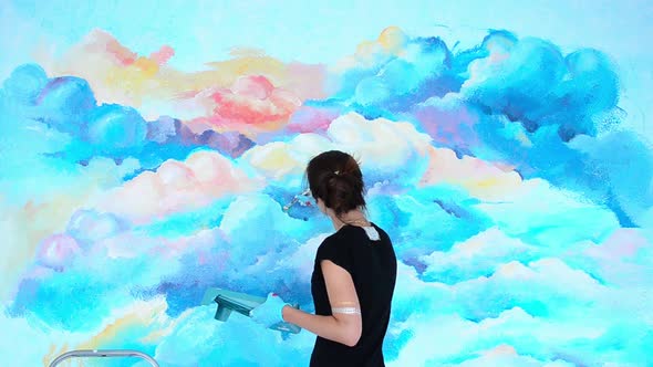 Woman the Artist Paints the Wall in to the Sky with Brush