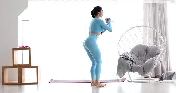Young fitness woman doing squat exercises with lunges from leg to leg.