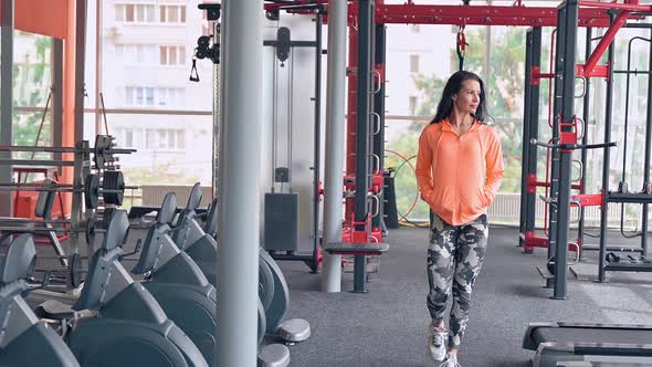 Woman Walks Through Fitness Equipment in Sport Gym