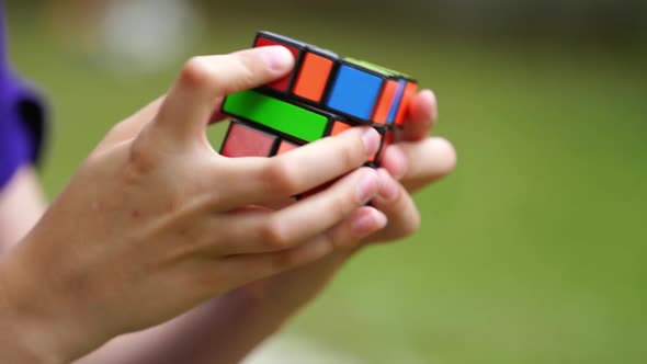 Boy practices with difficult Rubik's Cube. Smart teenager solving puzzle game with new Rubik's cube alt