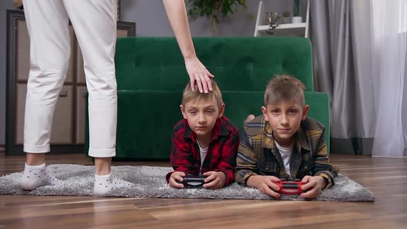 Teen Brothers Lying on the Floor and Playing Video Games Using Gamepads alt