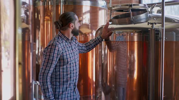 Portrait of Happy Male Brewer Admiring New Equipment in Brewery Smiling Walking at Large Beer Tanks alt