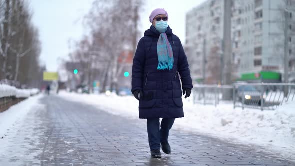 Elderly Woman in a Medical Face Mask Is Walking the Street alt