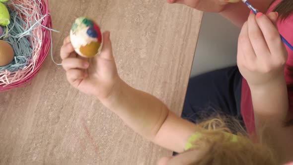 Top View of the Hands of Girls Who Paint Eggs with Paint