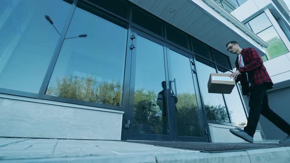 Delivery Man Leaves a Box Near Door Outside. alt