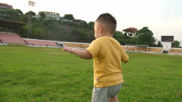 Asian Little Boy Running On The Grass At Stadium alt