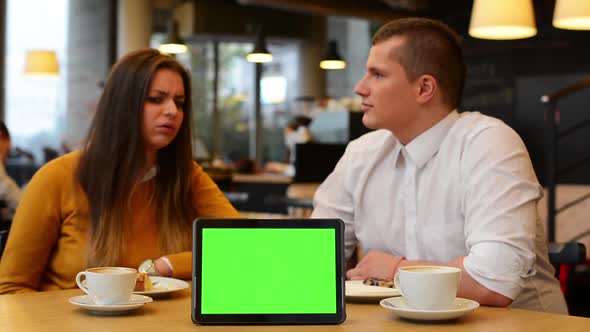 Tablet Green Screen, Happy Couple Smiles To Camera in Cafe, Coffee and Cake alt