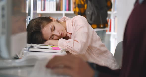 Young Tired Female Student Sleeping at Desktop in Library alt