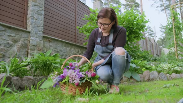 Woman Gardener Florist in Garden with Basket of Fresh Plucked Garden Spring Flowers alt