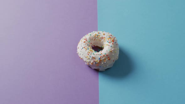 Video of donut with icing on purple and blue background alt