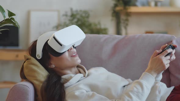 Woman Playing Game with VR Headset and Gamepad at Home alt