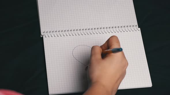 Girl Draws a Heart and Tears Out a Page From a Notebook alt