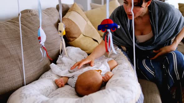 Young woman putting her baby in crib to sleep on sofa 4k alt